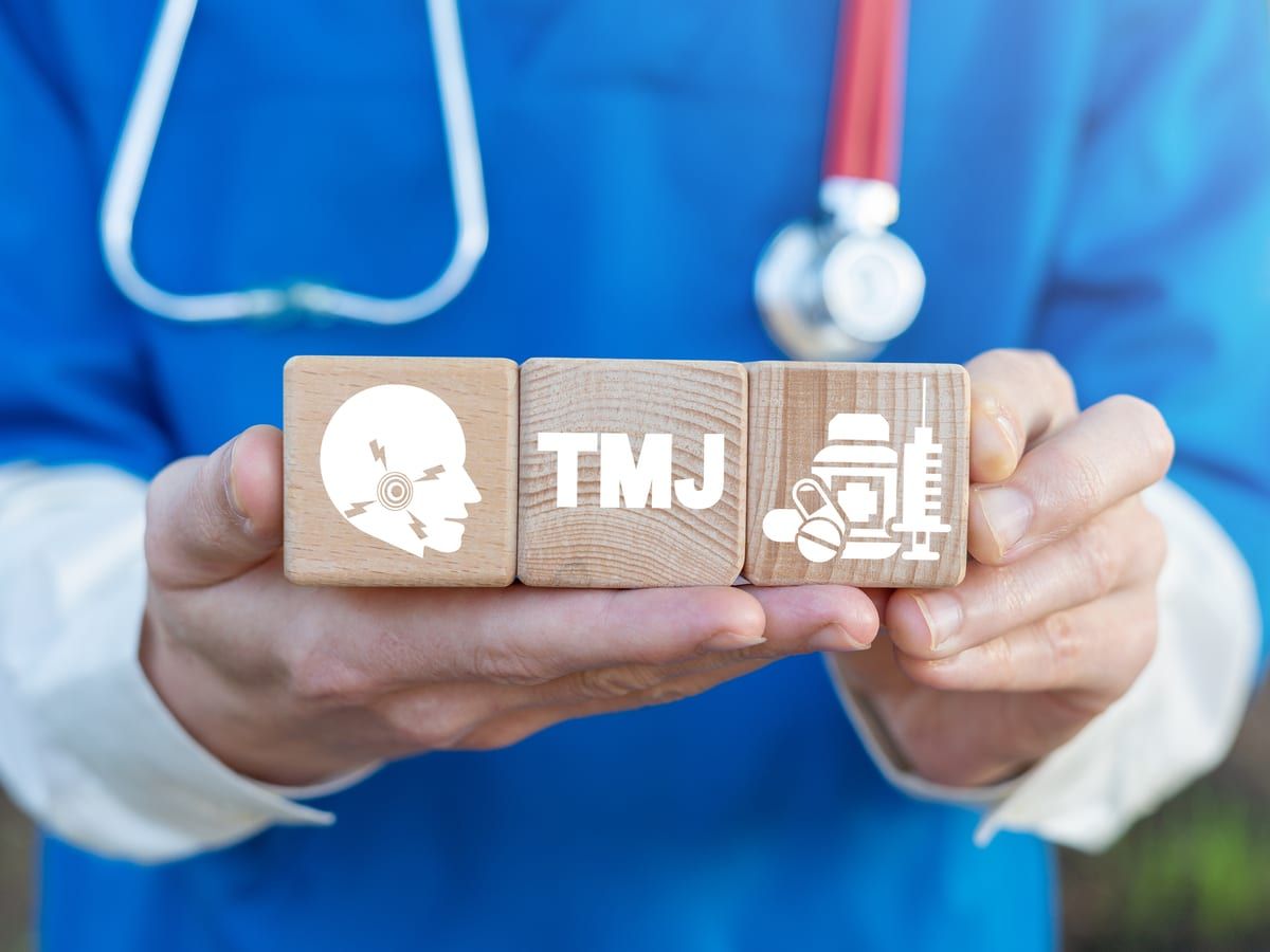 Doctor holding wooden blocks that say TMJ and show related images