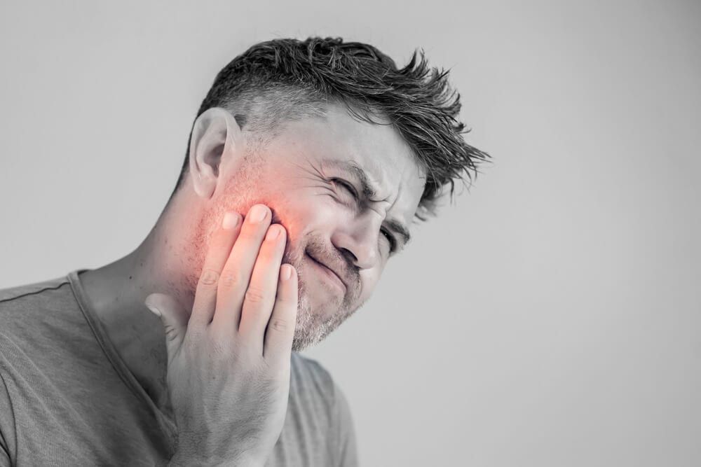 Man holding his cheek in pain