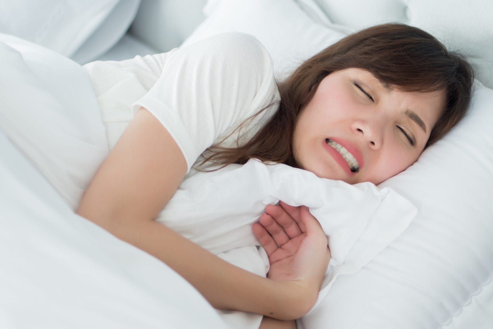woman sleeping and clenching her teeth together