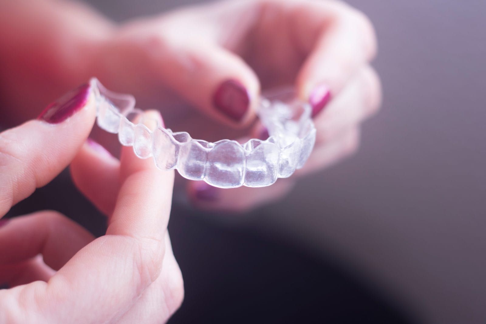 woman holding a clear orthodontic aligner